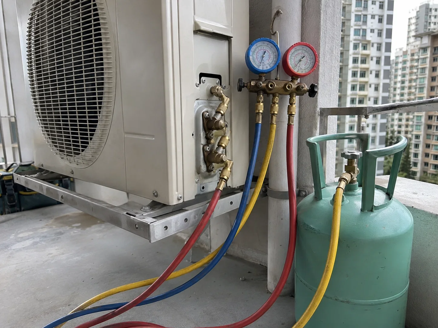 Aircon refrigerant service equipment connected to an outdoor unit in Singapore.