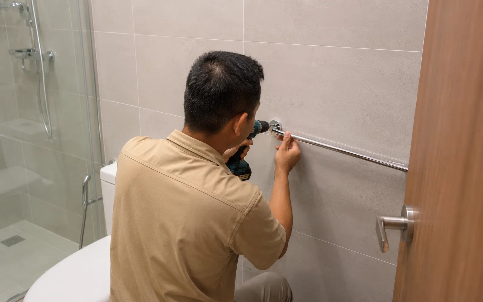 Technician installing bathroom accessories in Singapore.