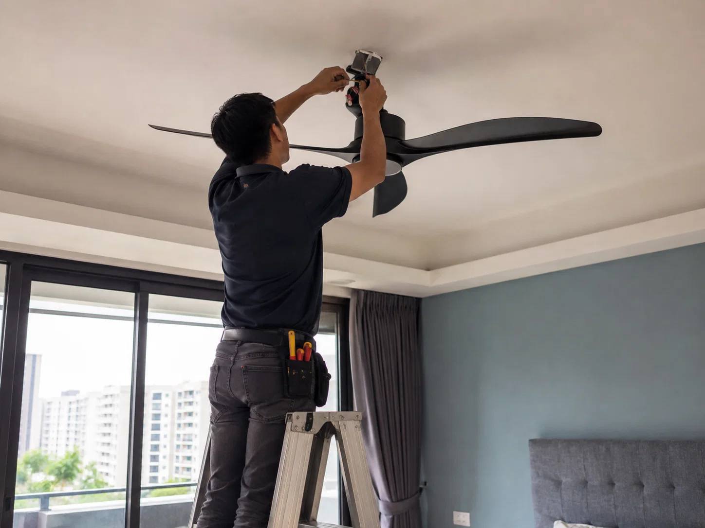 Technician installing a ceiling fan in Singapore.