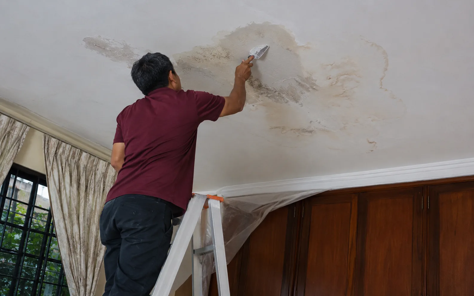 Technician repairing ceiling leakage in Singapore.