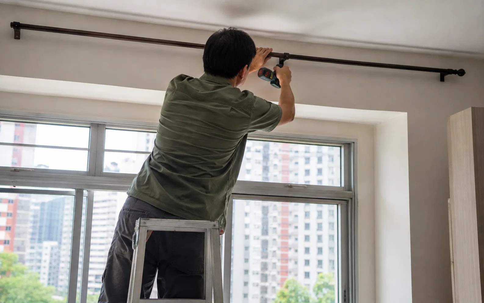 Technician installing a curtain rod in Singapore.