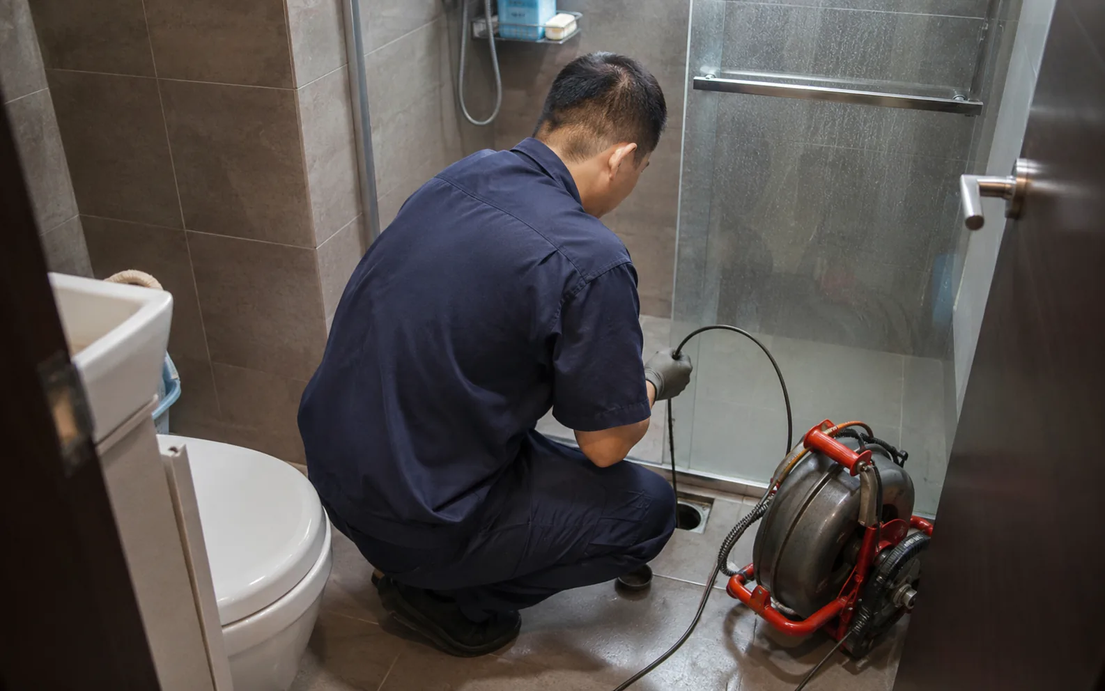 Technician clearing a floor trap choke in Singapore.