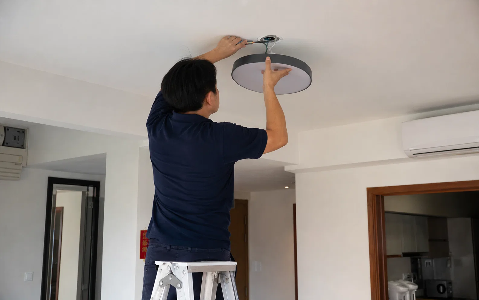 Technician installing a ceiling light fitting in Singapore.