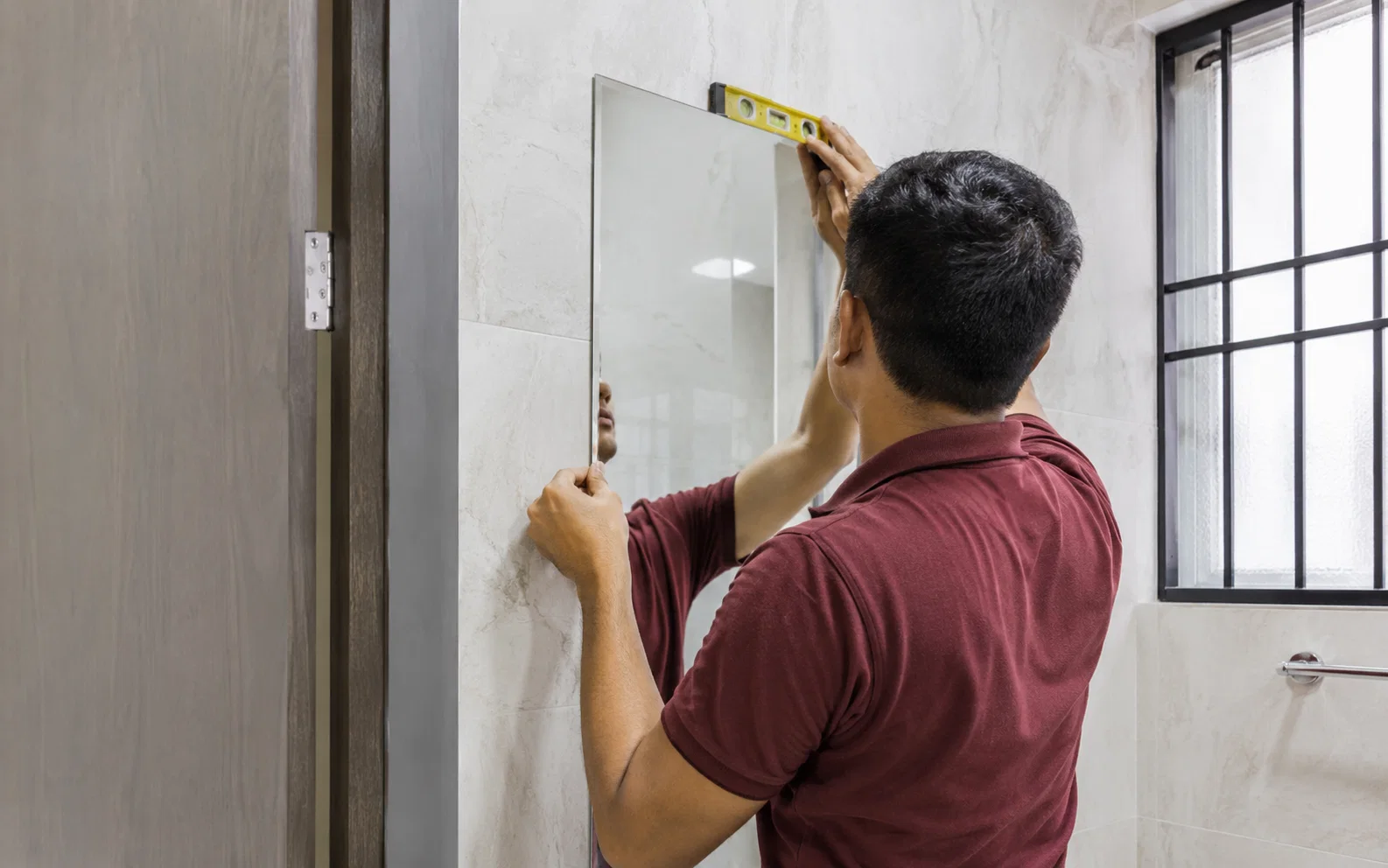 Technician installing a wall mirror in Singapore.