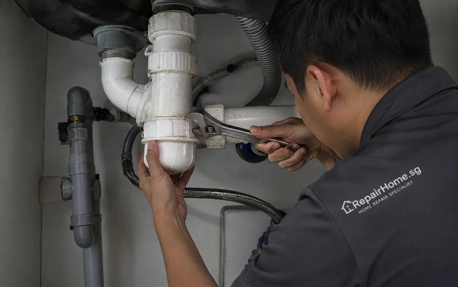 Plumber repairing a leaking household pipe in Singapore.