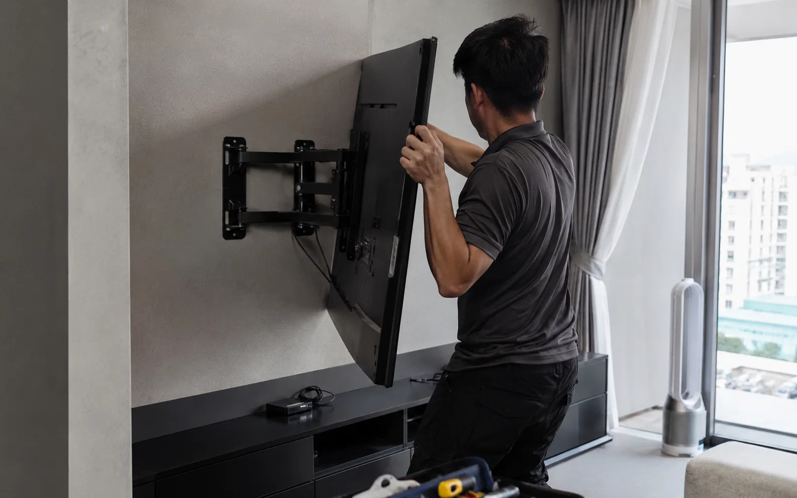 Technician installing a TV on a wall bracket in Singapore.